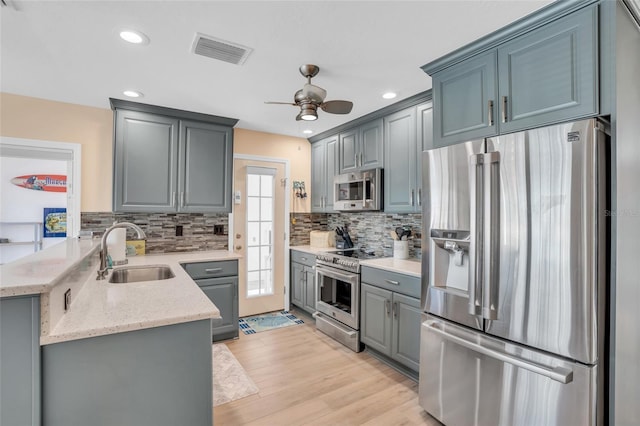 kitchen with appliances with stainless steel finishes, tasteful backsplash, gray cabinetry, ceiling fan, and sink