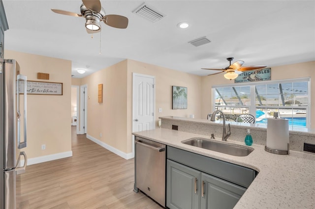 kitchen featuring appliances with stainless steel finishes, light stone counters, gray cabinetry, sink, and light hardwood / wood-style floors