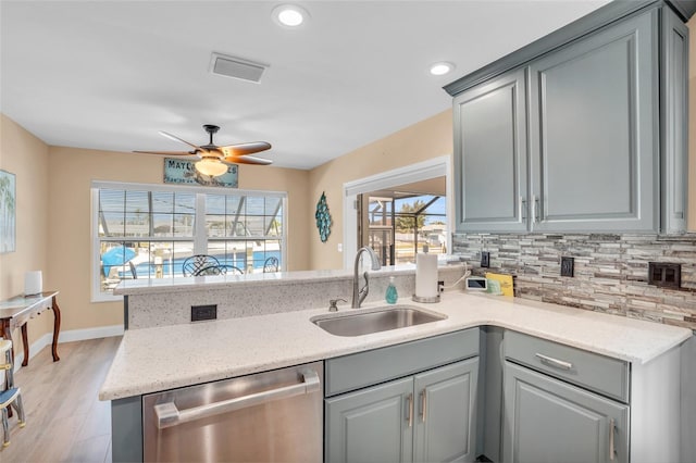 kitchen featuring stainless steel dishwasher, gray cabinetry, sink, and tasteful backsplash