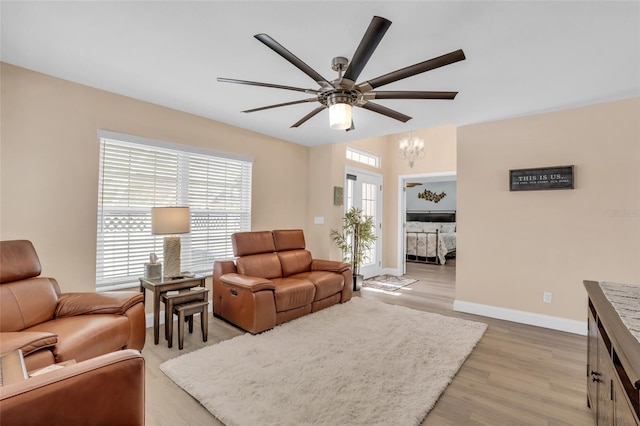 living room featuring light hardwood / wood-style floors and ceiling fan with notable chandelier