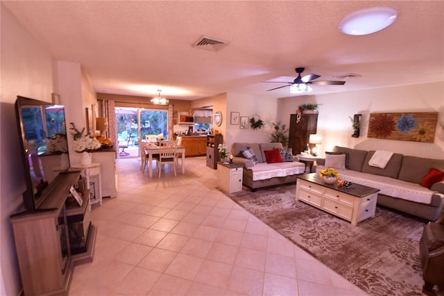 tiled living room with ceiling fan with notable chandelier and a textured ceiling