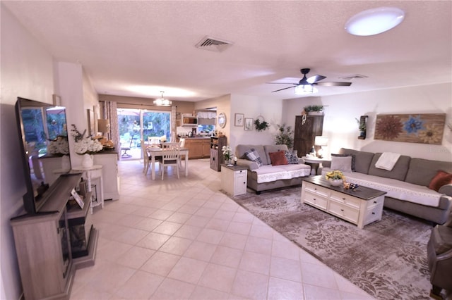 living area with a textured ceiling, light tile patterned flooring, visible vents, and ceiling fan