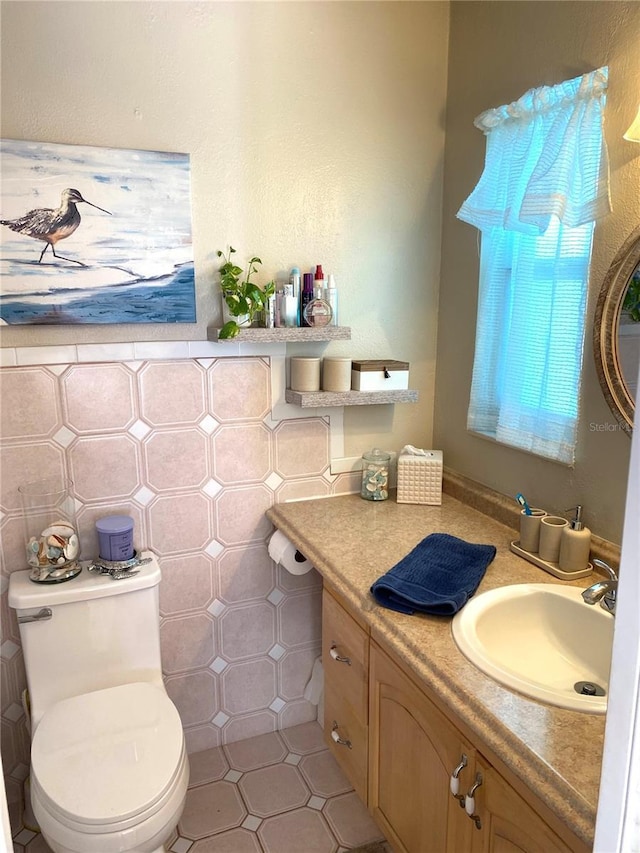 bathroom featuring tile patterned floors, vanity, toilet, and tile walls