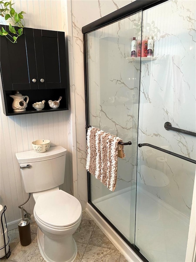 bathroom featuring a marble finish shower and toilet