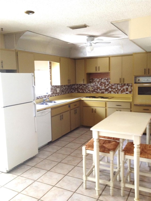 kitchen with white appliances, backsplash, ceiling fan, and cream cabinets