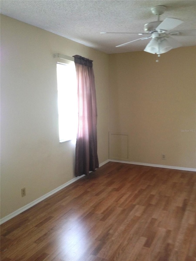 empty room featuring ceiling fan, wood finished floors, baseboards, and a textured ceiling