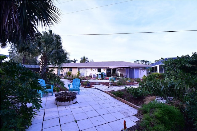 rear view of property featuring a fire pit and a patio area