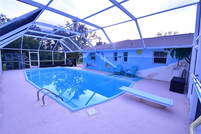 pool with glass enclosure, a patio area, and a diving board