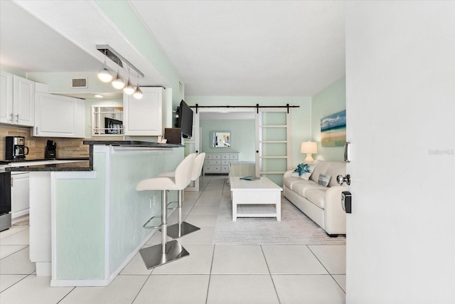 kitchen featuring white cabinetry, a kitchen breakfast bar, a barn door, decorative light fixtures, and decorative backsplash