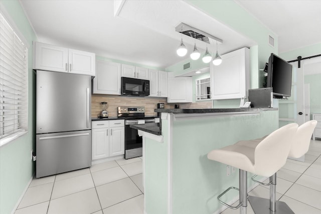 kitchen featuring appliances with stainless steel finishes, a breakfast bar, a barn door, decorative light fixtures, and white cabinets