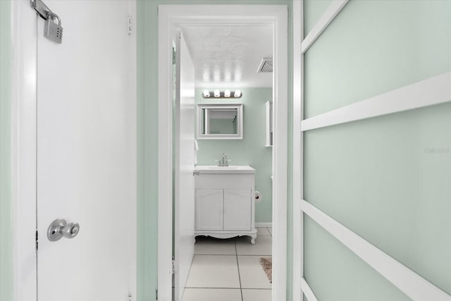 hall featuring sink, light tile patterned flooring, and a textured ceiling