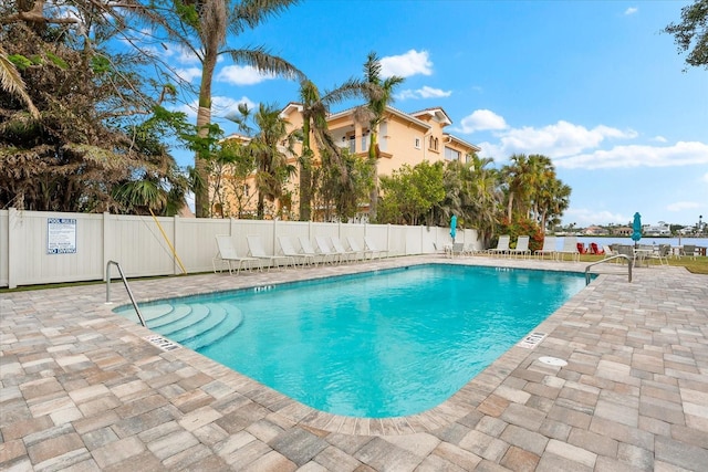 view of swimming pool with a patio area and a water view