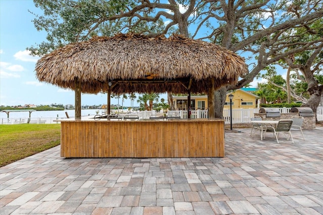 view of patio featuring area for grilling, a water view, and exterior bar