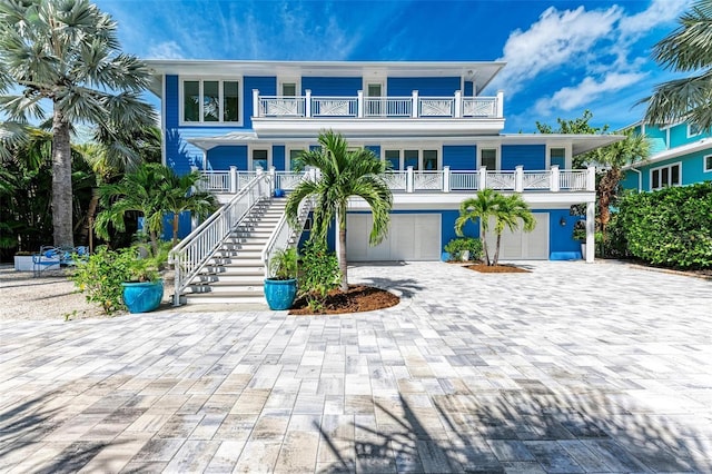 coastal home featuring a balcony, a garage, and covered porch