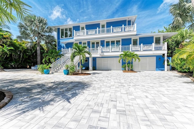 beach home with a balcony, covered porch, and a garage