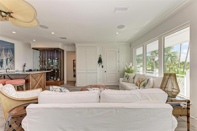 living room featuring light hardwood / wood-style flooring, crown molding, and sink