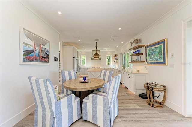 dining area featuring crown molding and light hardwood / wood-style flooring