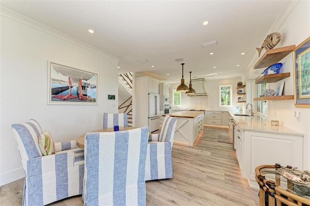 dining space with sink, light hardwood / wood-style floors, and ornamental molding