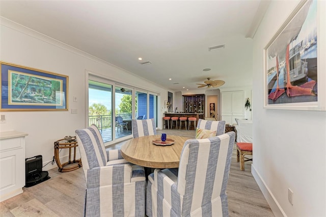 dining space with ceiling fan, ornamental molding, and light hardwood / wood-style flooring