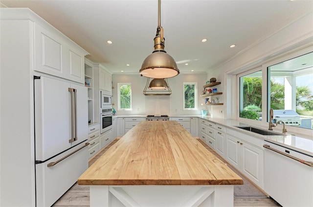 kitchen with wood counters, white appliances, white cabinets, decorative light fixtures, and a kitchen island