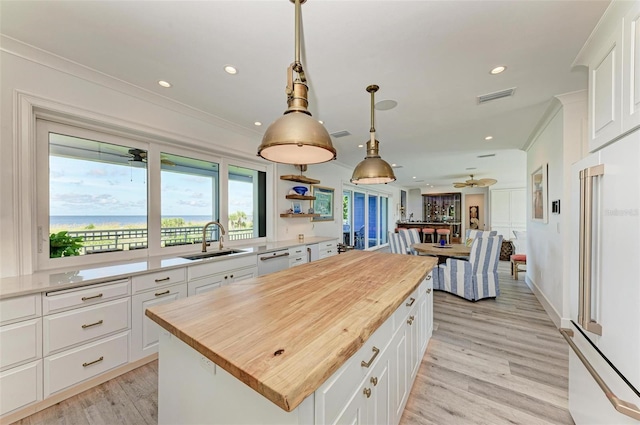 kitchen with white cabinetry, a center island, sink, butcher block countertops, and white appliances