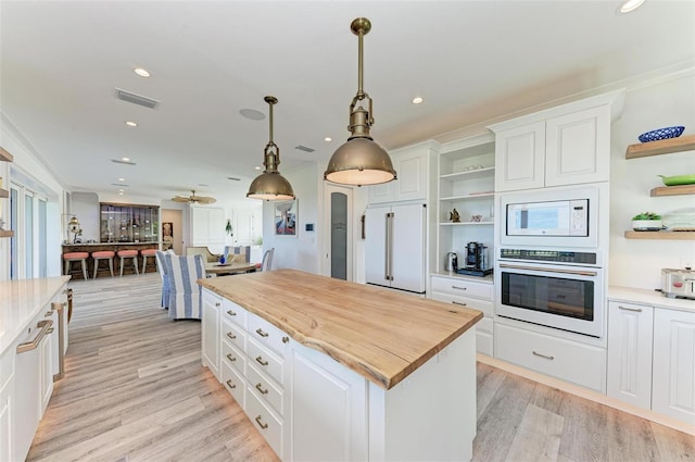 kitchen featuring wood counters, pendant lighting, built in appliances, white cabinets, and a kitchen island