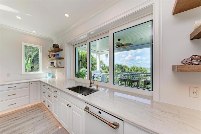 kitchen with stainless steel dishwasher, light stone counters, ceiling fan, sink, and white cabinetry