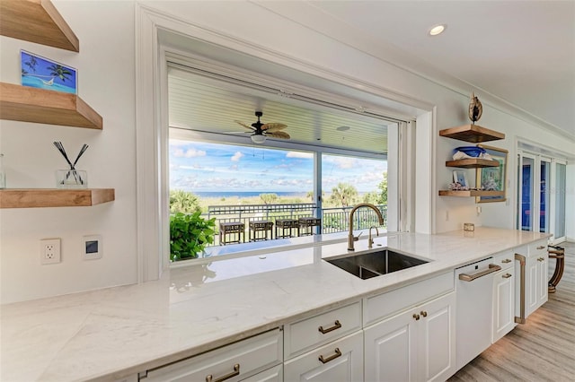 kitchen featuring light stone countertops, white dishwasher, ceiling fan, sink, and white cabinets