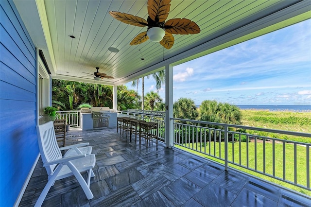 deck with area for grilling, a water view, exterior kitchen, and a yard