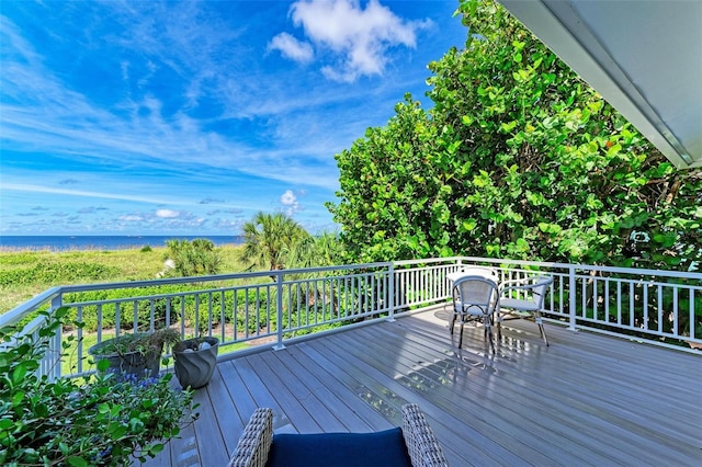 wooden terrace featuring a water view and a beach view