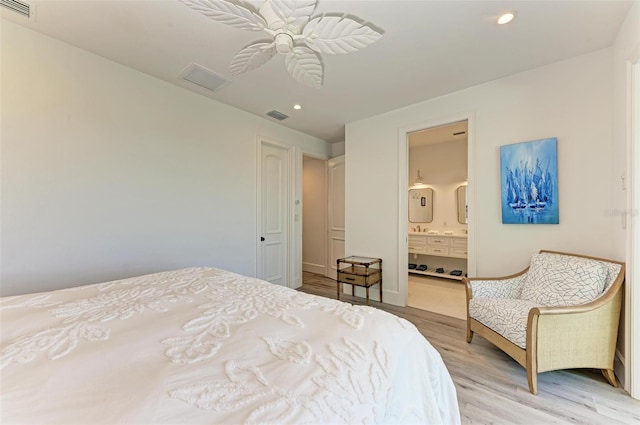 bedroom with ensuite bathroom, light hardwood / wood-style flooring, and ceiling fan