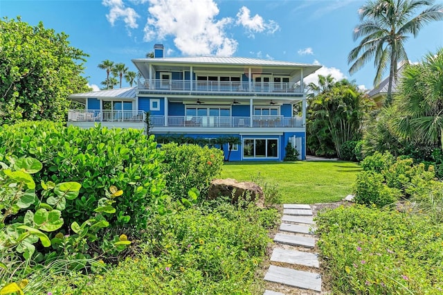 back of house with a lawn and a balcony