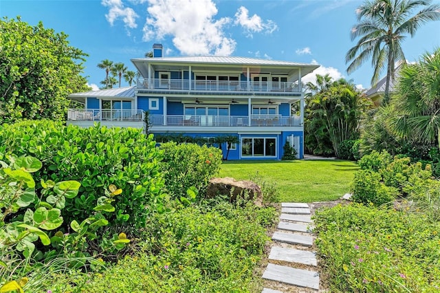 506 S Casey Key Rd, Nokomis, FL 34275 - back of house with a ceiling fan, a balcony, a lawn, metal roof, and a chimney
