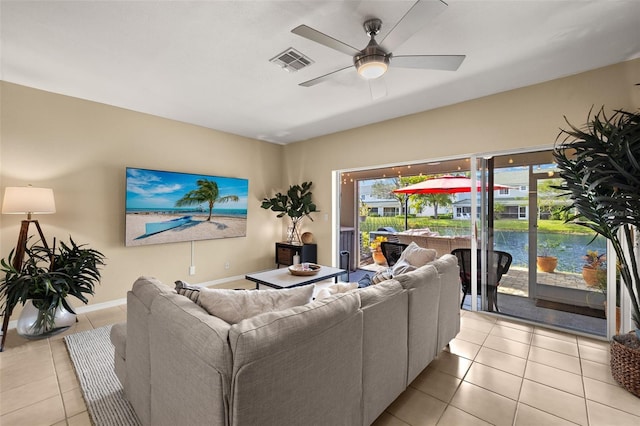 tiled living room with ceiling fan and a water view