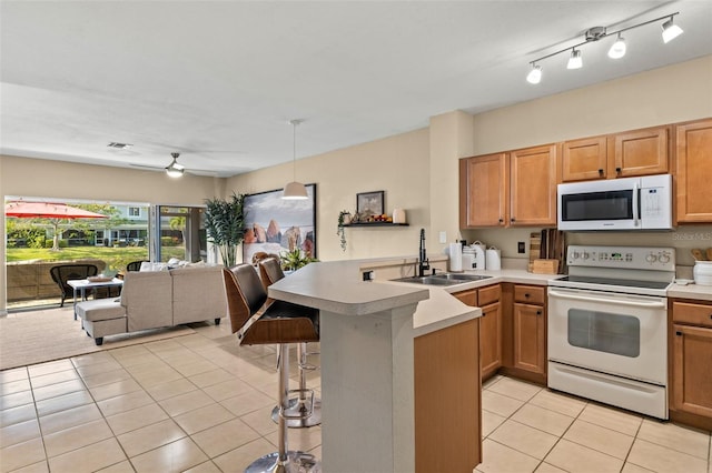 kitchen featuring white appliances, sink, hanging light fixtures, kitchen peninsula, and light tile patterned flooring