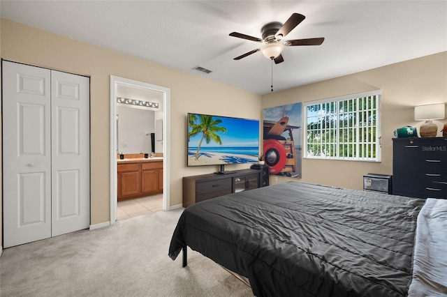 bedroom with ceiling fan, a closet, connected bathroom, and light colored carpet