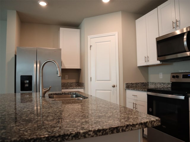 kitchen featuring dark stone counters, white cabinetry, sink, and stainless steel appliances