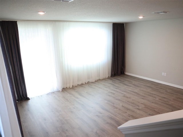 spare room featuring hardwood / wood-style floors and a textured ceiling