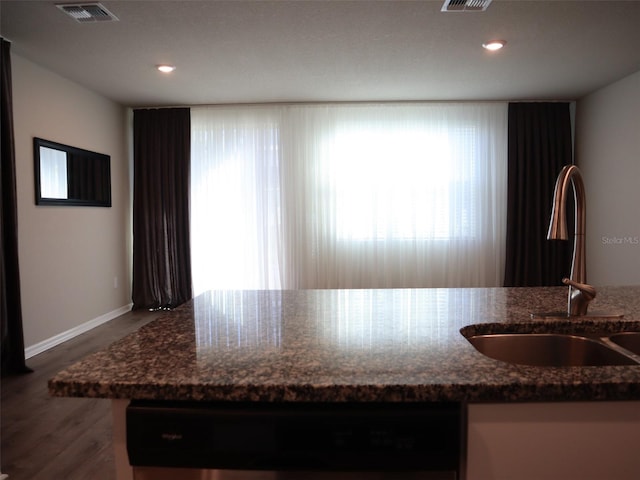 kitchen with dishwasher, hardwood / wood-style floors, dark stone counters, and sink