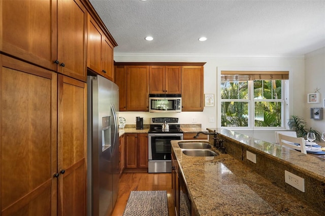 kitchen with stone counters, ornamental molding, sink, and appliances with stainless steel finishes