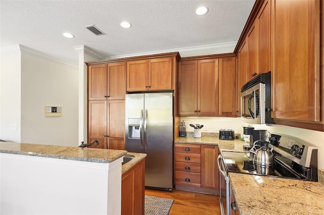 kitchen with light wood-type flooring, light stone countertops, ornamental molding, and appliances with stainless steel finishes