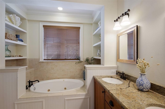 bathroom with built in shelves, ornamental molding, vanity, and tiled bath