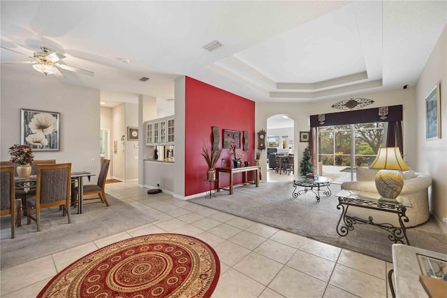 tiled living room featuring ceiling fan and a raised ceiling