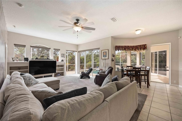 tiled living room featuring ceiling fan and a textured ceiling