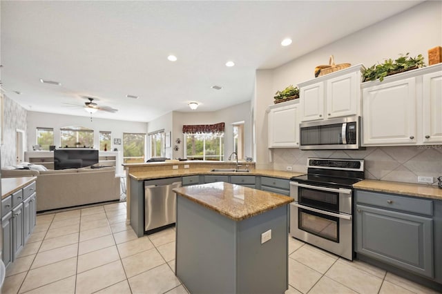 kitchen with appliances with stainless steel finishes, a kitchen island, white cabinetry, and gray cabinetry