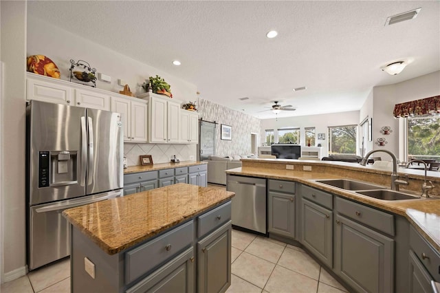 kitchen with gray cabinetry, white cabinets, sink, a kitchen island, and stainless steel appliances