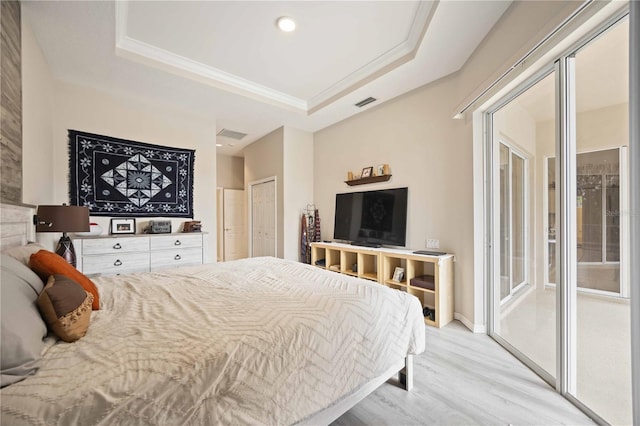 bedroom featuring light hardwood / wood-style floors, ornamental molding, access to outside, and a tray ceiling