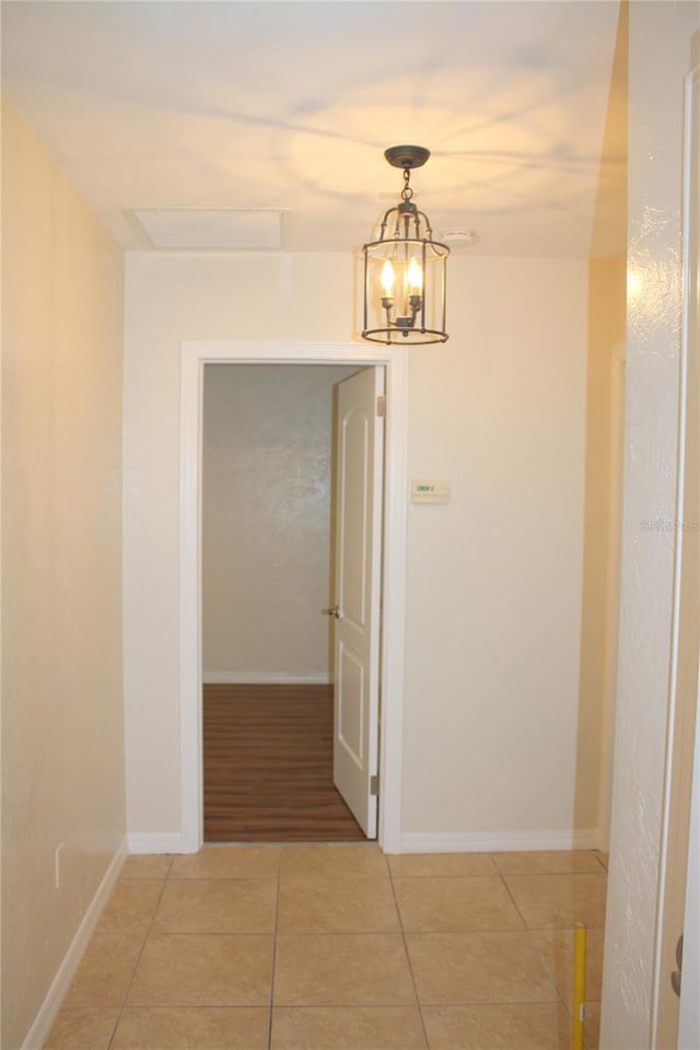 hall with tile patterned floors and a chandelier