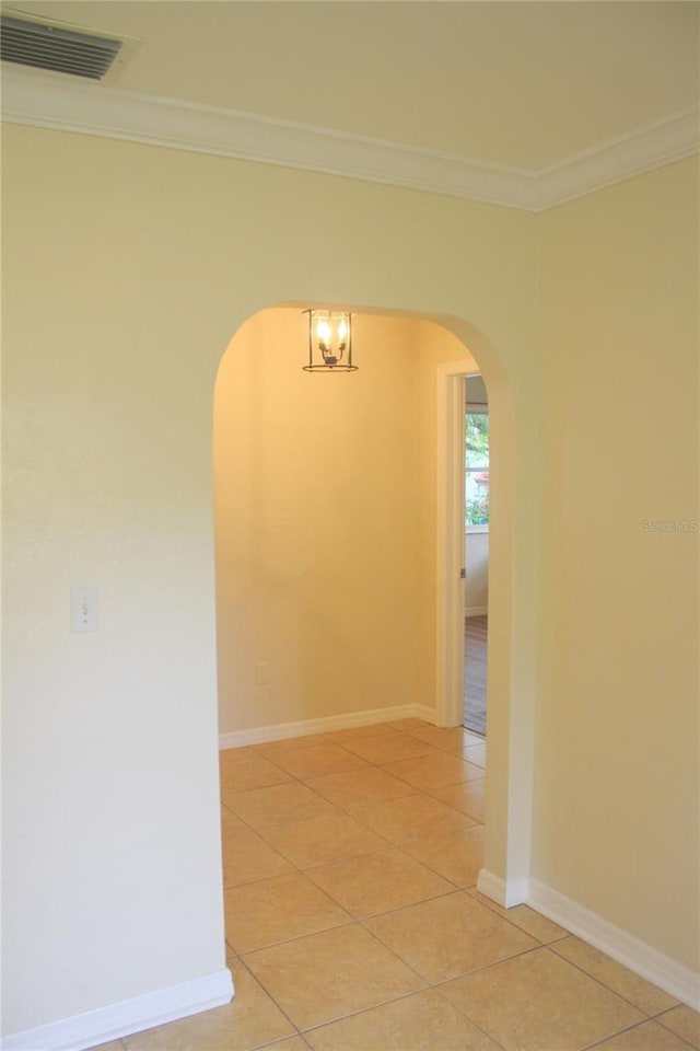 tiled empty room featuring ornamental molding