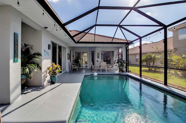 view of swimming pool with ceiling fan, glass enclosure, and a patio